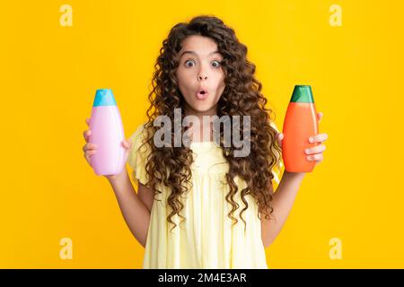 Teenage girl with shampoos conditioners or shower gel. Kids hair care cosmetic product, shampoo bottle. Amazed surprised emotions of young teenager Stock Photo
