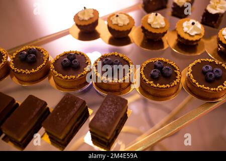 Assortment of delicious dessert, chocolate cakes, tarts with fresh berry, cupcakes with mousse on glass tray. Festive candy bar, buffet sweet bar. Per Stock Photo