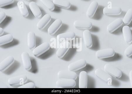Full Frame White Pills Dropped Against White Marble Backgrounds, Concept of healthy eating, disease prevention, and treatment, Taking supplements Stock Photo