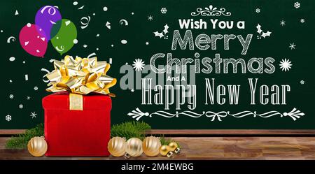 Christmas decoration background with gift box and  chalkboard Merry Christmas message, decorated pine leaves and baubles on wood table with copy space Stock Photo