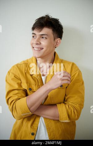 Portrait of happy young man in yellow demin jacket looking away Stock Photo