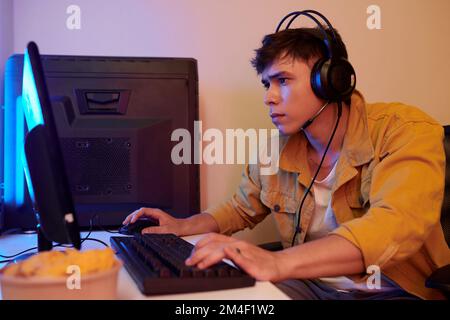 Serious young man wearing headset when playing videogame at home Stock Photo