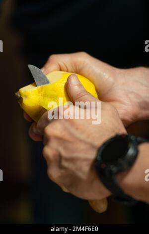 Close up of a person peeling fruit with a small sharp knife Stock Photo