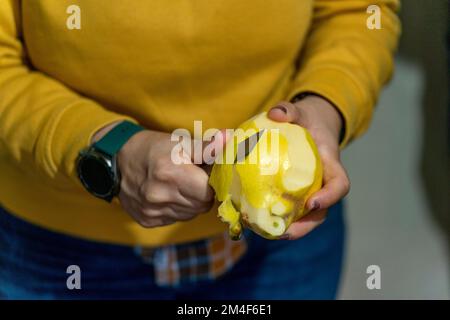 Close up of a person peeling fruit with a small sharp knife Stock Photo
