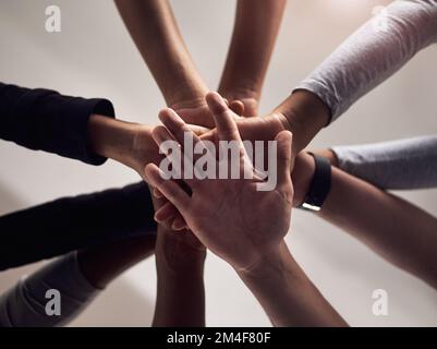 Get hands on with getting fit. a group of people joining their hands together in solidarity at a gym. Stock Photo