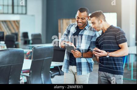 Collaborating with their connections. two young designers using digital devices in an office. Stock Photo