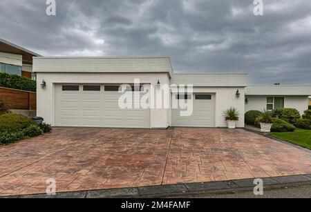 Residential house two car garage. Modern and luxurious double garage with driveway and roller door. Fragment of a luxury house with a garage door. Nob Stock Photo