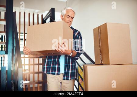 Carrying precious cargo aka memories. a handsome mature man carrying a box on moving day. Stock Photo