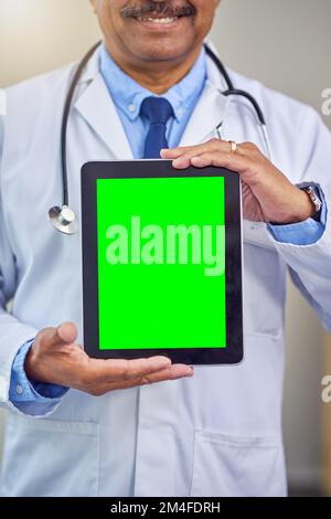 Medical information is part of the process. an unrecognizable male doctor holding up a digital tablet in front of him while standing inside of a Stock Photo