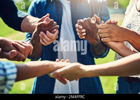 Its better if we stick together. Closeup shot of an unrecognizable group of people holding hands outdoors. Stock Photo