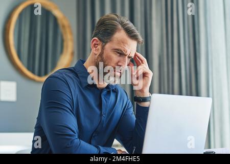 This laptop frustrates me sometimes. a cheerful middle aged businessman working on his laptop and paying bills with his credit card at home during the Stock Photo