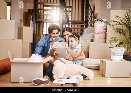 Waiting for the movers to arrive. Full length shot of an affectionate young family unpacking their boxes on moving day. Stock Photo