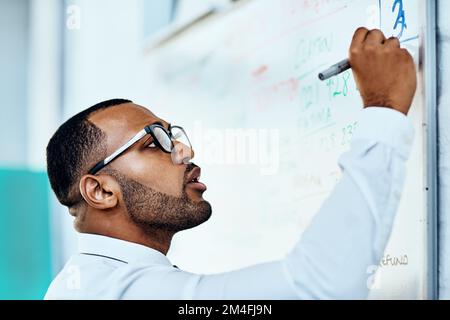 I need to change this around. a handsome young businessman standing alone in his office and writing on a white board. Stock Photo