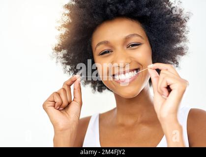 How I get my sparkly white teeth. an attractive young woman flossing in the bathroom at home. Stock Photo