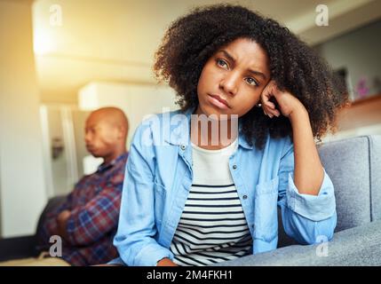 Whats going on in that min of yours. an unhappy looking young woman seated on a couch while contemplating at home during the day. Stock Photo