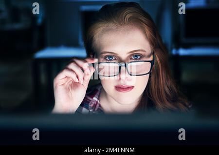 Shell be watching you. Portrait of a focused young female programmer working on a computer in the office at work during the night. Stock Photo