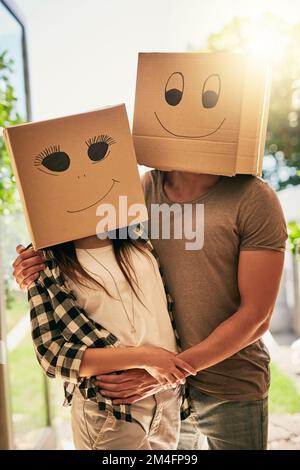 Meet the smileys. a couple wearing boxes with smiley faces drawn on them on their heads. Stock Photo