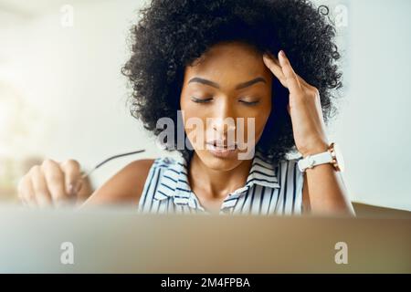 This headache is not helping my creative process. a young female designer experiencing a headache in a modern office. Stock Photo
