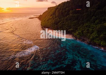 Beautiful ocean coastline with beach and bright warm sunset in Bali. Aerial view Stock Photo