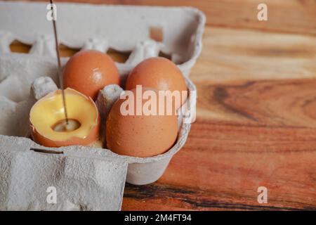 woman beating an egg in its own shell with a small blender, several eggs in an eggcup Stock Photo