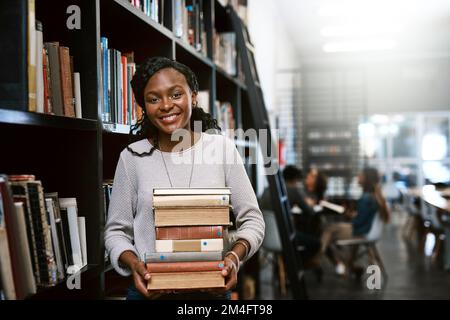 You dont have to look far to find the answers. Portrait of a happy young woman carrying books in a library at college. Stock Photo