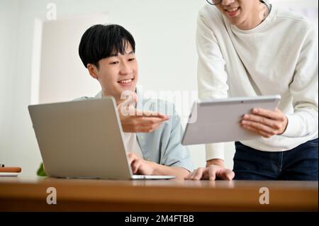 Two young Asian male college students or office employees discussing and brainstorming on their project together. Stock Photo