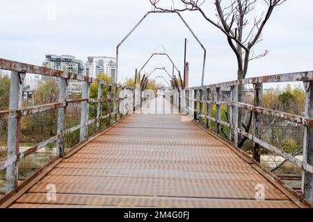 Old rusted metallic rusted bridge over the train lines in Obor area in Bucharest, Romania, in a cloudy autumn day Stock Photo