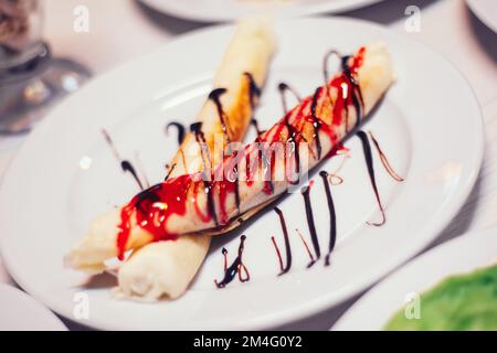 thin blinchiki with sweet sauce, hamburger and other dishes on the table in the cafe Stock Photo
