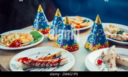 funny hats and delicious dishes on the festive table Stock Photo