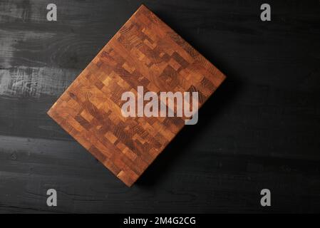 Empty wood cutting board on black background. Stock Photo