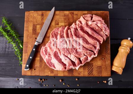 Fresh raw beef steak on wooden cutting board, top view. Served over black background. Web design banner with copy space. Organic healthy fresh food Stock Photo