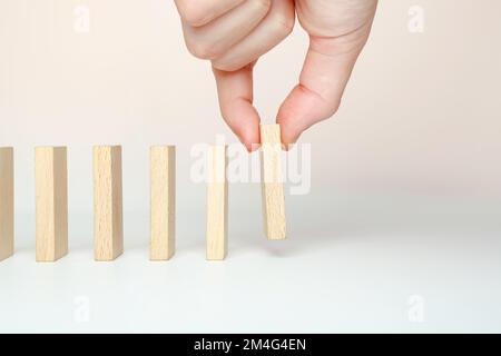 A business concept with a domino effect. The hand puts dominoes to make a chain reaction Stock Photo