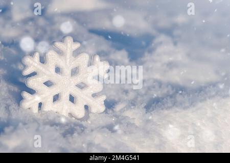 Christmas background with decorative snowflakes on snow. Christmas decoration on natural snow. A snowflake in the snow. Festive background for the design.  Stock Photo