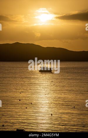 Schull, West Cork, Ireland. 21st Dec, 2022. The sun rises from behind clouds over moored fishing trawler 'Laetitia' in Schull Harbour on the shortest day of the year. Credit: AG News/Alamy Live News Stock Photo