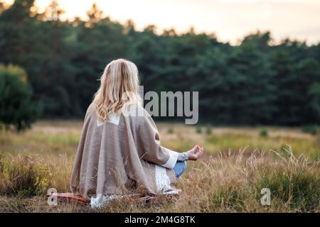 Woman meditating and practicing yoga in lotus position. Mental health exercise outdoors Stock Photo