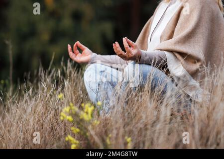 Woman practicing yoga exercise in lotus position. Relaxation and meditation outdoors Stock Photo