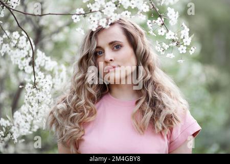 Portrait of beautiful woman with spring flowering tree. Girl with long hair in white bloom Stock Photo