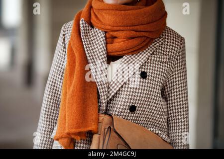 Close up knitted wool ochre scarf and double breasted houndstooth jacket with buttons. Stylish fashion trend details Stock Photo