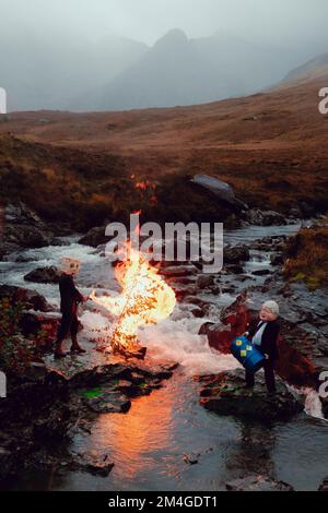 Scotland, UK. 25th October 2021. A person posing as Boris Johnson and another with an oil tank for a head light fire and dump fake toxic waste in the Fairy Pools in a theatrical action staged by members of Ocean Rebellion a sister group to Extinction Rebellion ahead of the COP26 conference in Glasgow. Stock Photo