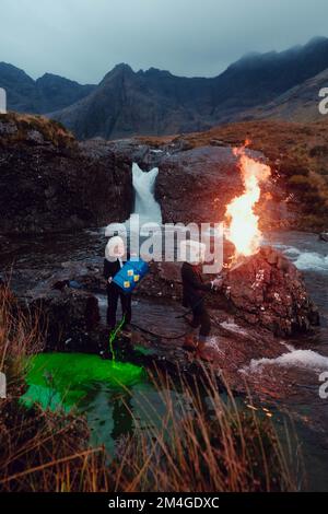 Scotland, UK. 25th October 2021. A person posing as Boris Johnson and another with an oil tank for a head light fire and dump fake toxic waste in the Fairy Pools in a theatrical action staged by members of Ocean Rebellion a sister group to Extinction Rebellion ahead of the COP26 conference in Glasgow. Stock Photo