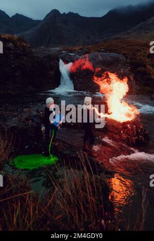 Scotland, UK. 25th October 2021. A person posing as Boris Johnson and another with an oil tank for a head light fire and dump fake toxic waste in the Fairy Pools in a theatrical action staged by members of Ocean Rebellion a sister group to Extinction Rebellion ahead of the COP26 conference in Glasgow. Stock Photo