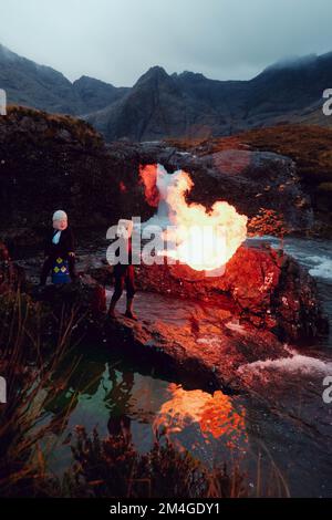 Scotland, UK. 25th October 2021. A person posing as Boris Johnson and another with an oil tank for a head light fire and dump fake toxic waste in the Fairy Pools in a theatrical action staged by members of Ocean Rebellion a sister group to Extinction Rebellion ahead of the COP26 conference in Glasgow. Stock Photo