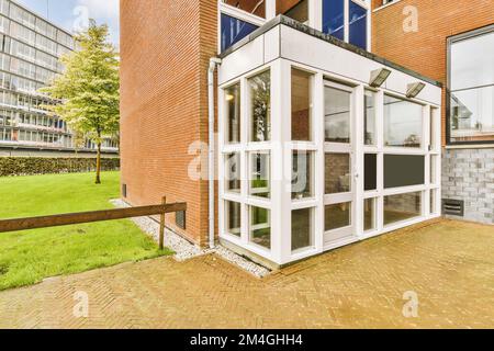 a brick building with glass doors on the outside and green grass in the front yard, as well viewed from inside Stock Photo