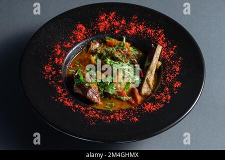 stew soup with vegetables, beef ribs and cilantro in black plate at restaurant Stock Photo