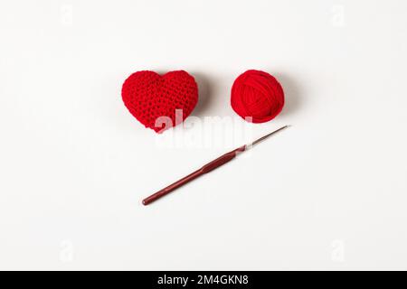 Croched red heart on a gray background and and a ball of thread with a ...