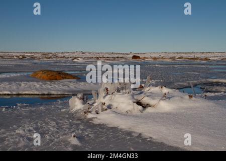 Arctic landscape - frozen arctic tundra in Nunavut over a snow covered waterbody on a clear cold day, near Arviat, Nunavut Stock Photo