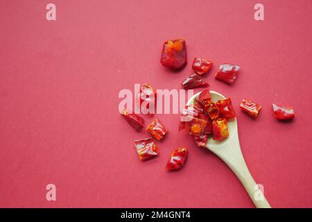 red chili flakes spilling on red background  Stock Photo