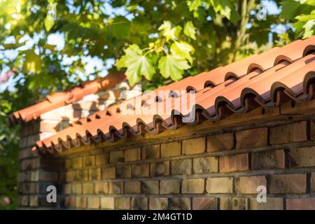 A fragment of a brick fence covered with red tiles. Stock Photo