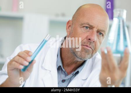 mature male scientist examining liquid in erlenmeyer flask Stock Photo