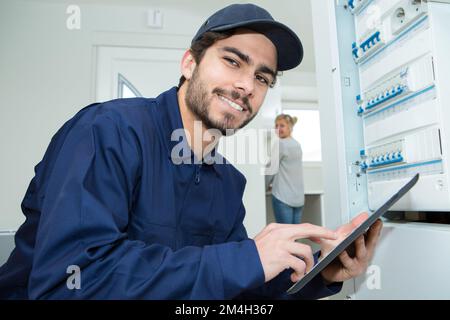 electrician with tablet posing next to fuse box Stock Photo